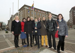 Transidenten-Organisationen Lili Marlene und Transbekannt hissen zusammen mit Unterstützerinnen und Unterstützern Regenbogenfahne am Rathaus