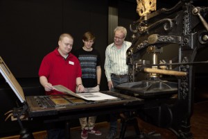 Besucher in der Ausstellung an einer Handdruckpresse aus dem 19. Jahrhundert. Foto: Technoseum 