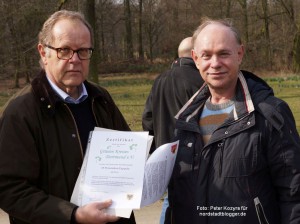 Reinhard Budde (links), Vorstandsmitglied vom Grüner Kreis e.V., nimmt das Zertifikat für die Baumspenden im Fredenbaumpark von Michael Stoeckert, dem Fachleiter des Tiefbauamt-Bereichs Stadtgrün, entgegen.