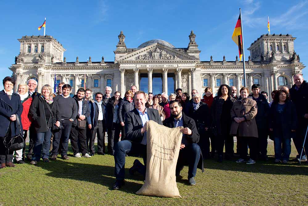 Gemeinsam mit Vertretern von Integrationsvereinen füllte Hoffmann Erde ins Kunstwerk 'Der Bevölkerung' ein. Foto: Wolf-Dieter Blank