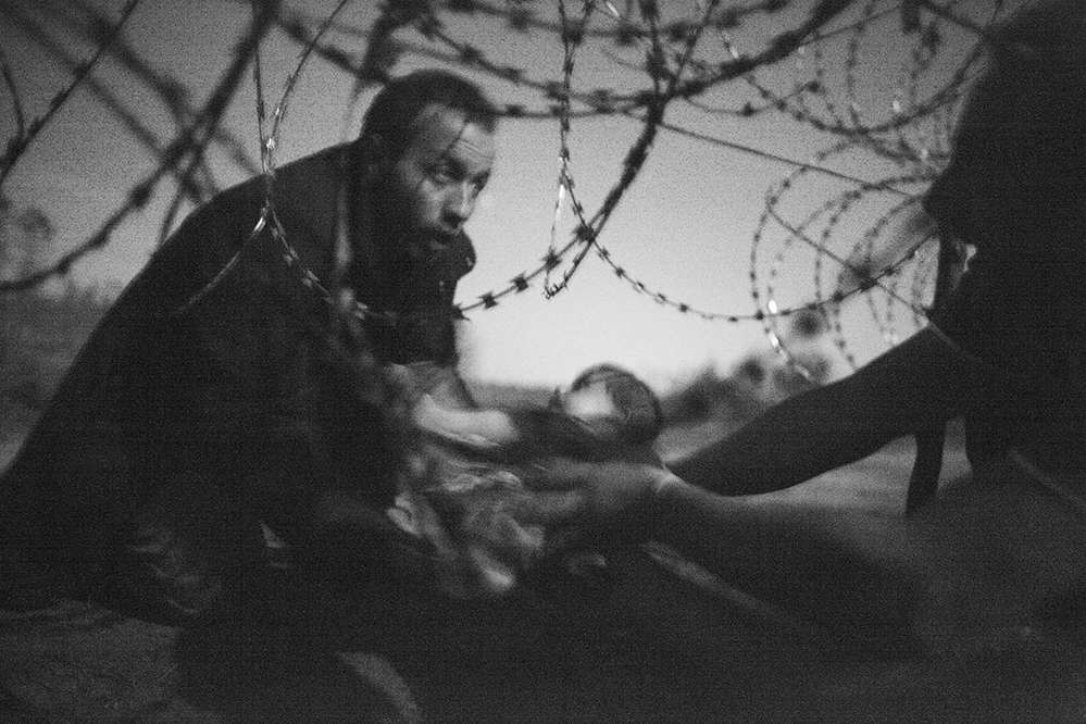 Ein Foto des australischen Fotografen Warren Richardson hat den World Press Photo Wettbewerb 2015 gewonnen. Das Foto zeigt einen Mann, der an der ungarisch-serbischen Grenze in Röszke ein Baby durch den Grenzzaun reicht.