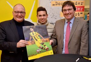 BVB-Spieler Raphael Guerreiro (Mitte) unterschrieb im Katholischen St.-Johannes-Hospital den BVB-Posterkalender zugunsten des Hilfsfonds‘ „Dortmunder Kinder in Not“, hier mit Propst Andreas Coersmeier (links) und Klaus Bathen, Hauptgeschäftsführer der Kath. St.-Johannes-Gesellschaft. Foto: pdp