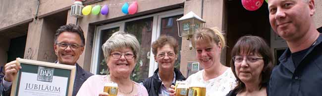 Alexander Beckmann-Olschowka von den Dortmunder Brauereien (li.) und Christian Krieg von Getränke Weidlich (re.) gratulieren Wirtin Renate Schimm (2.v.l.) und dem Team der Eckkneipe „Zur Palette“ zum Jubiläumstag. Foto: p:e:w