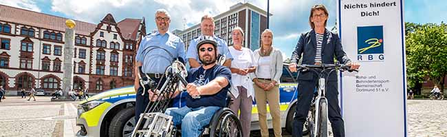 Ralf Lindemann (Polizei Dortmund), Frank Wolff (Polizei Dortmund), Christiane Vollmer (Behindertenbeauftragte der Stadt Dortmund), Julia Verbeck (2. Vorsitzende der Behindertensport-Gemeinschaft Dortmund 51 e.V.), sowie Schirmherrin Birgit Jörder (v.l.n.r.) präsentierten heute das Programm zusammen mit dem Fahrer des Handbike Stephan Blank (vorne). Foto: Roland Gorecki