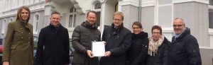 Planungsdezernent Ludger Wilde (Mitte) übergibt vor dem Hintergrund eines sanierten Wonblocks in der westlichen Innenstadt Förderzusagen über 5,3 Millionen Euro an Franz-Bernd Große-Wilde (Dritter von links), Vorstandsvorsitzender des Spar- und Bauvereins. Foto: Heike Thelen/ Stadt Dortmund