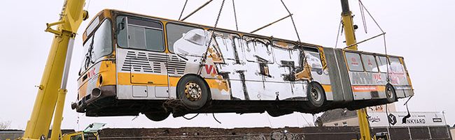 Bus wird am Junkyard über die Mauer gehoben