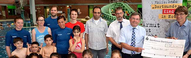 Spendenübergabe im Schwimmbad: Dr. Gert Fischer (2.v.r.), Vorstand der Marianne Hoffmann-Stiftung übergab im Nordbad eine große Spende an Alwin Buddenkotte (1.v.r.) und Thomas Renneke (3.v.r.) vom Hilfsfonds „Dortmunder Kinder in Not“. Darüber freuten sich besonders die Kinder des Schwimmkurses für Flüchtlinge mit Schwimmtrainerin Meike Beulshausen (1.v.l.) sowie Karina Breiling vom Verein „Projekt Ankommen e.V.“ (2.v.l.) sowie Helfer und Eltern. Foto: Michael Bodin /pdp
