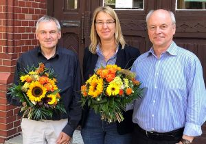 Abschied und Neustart am Schulmuseum: Rüdiger Wulf geht, Michael Dückershoff (links) übernimmt. Blumen gabs von Dr. Dr. Elke Möllmann. Foto: Joachim vom Brocke