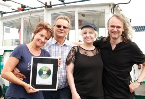 Steuerfrau Kerstin Weiß mit der gerahmten CD, Schiffseigner Eberhard Butenhof und kunstgruppe GOTTLIEB an Bord der MS Bayrischer Wald. Fotos: Karsten Wickern