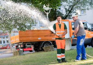 Patrick Michnikowski (Stadt Dortmund, li.) und Paul Maichrzik (DONETZ) bei der Installation und Bewässerung an der Landgrafen-Grundschule zur Rettung der Straßenbäume bei der Rekordhitze. (Foto: Frauke Schumann/ DEW21)