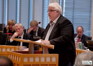 Heiner Garbe (AfD) rät in der Haushaltsdebatte dem Kämmerer Jörg Stüdemann (Im Hintergrund) sinngemäß, den Gürtel enger zu schnallen und strukturelle Einsparungen vorzunehmen.