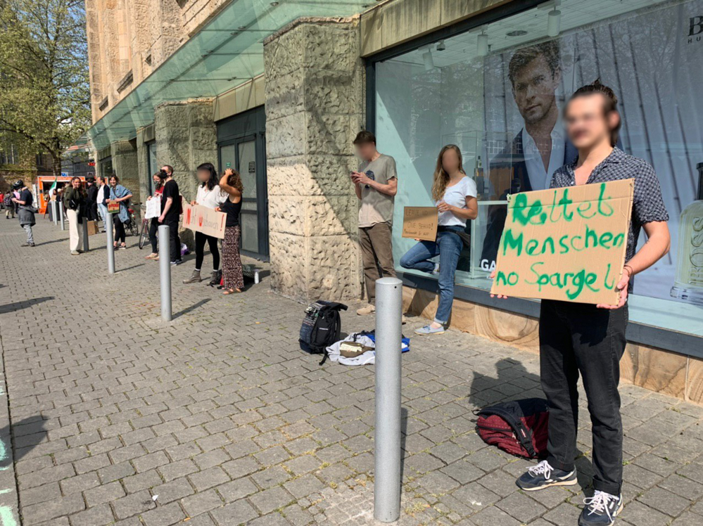 Etwa 25 Menschen haben sich mit Schildern vor einem Waffelstand aufgestellt. Fotos: Karsten Wickern