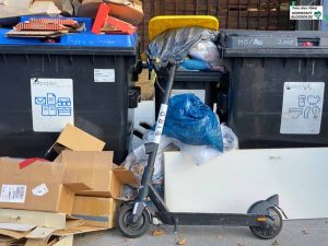 Ein symbolisches Bild: Ein E-Scooter auf dem Abfall. Viele Anwohner:innen haben den Kaffee auf. 