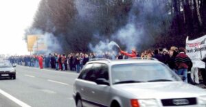 Belegschaftsteile der Westfalenhütte beim „Band der Solidarität“ gegen Zechenschließungen (1997). Die Menschenkettenaktion zog sich entlang der Bundesstraßen durch das gesamte Ruhrgebiet, wie hier in Dortmund. Mitarbeiter der Grubenfeuerwehr mit Handfackeln sorgten für zusätzliche Aufmerksamkeit.