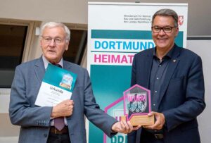 Willi Garth, 1. Vorsitzender des Hörder Heimatvereins, 2. Platz, erhält von OB Thomas Westphal den Pokal, einen Blumenstrauß und eine Urkunde.