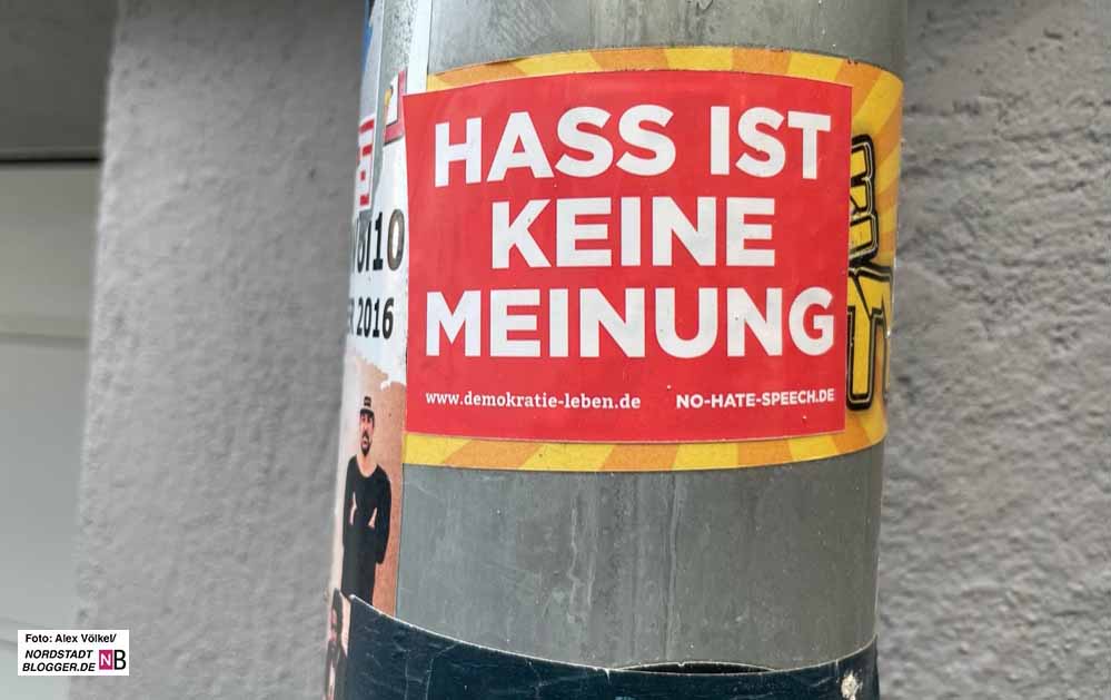 Das Bild zeigt eine Regenrinne mit einem roten Sticker. Darauf steht in großen weissen Buchstaben "Hass ist keine Meinung" sowie demokratie-leben.de und no-hate-speech.de