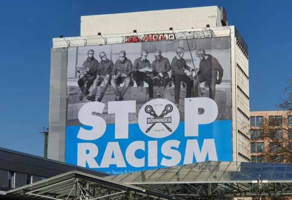 STOP RACISM! Es kann gar nicht groß genug geschrieben werden. 500 m2 sind jedoch ein kleiner Schritt in die richtige Richtung. Erneut setzt die Firma Bönninger Gerüstbau Dortmund am Hauptbahnhof mit Ihrem Plakat ein wichtiges Statement: STOP RACISM. Für diese Botschaft gab es viele positive Rückmeldungen, aber leider auch die ein oder andere negative Äußerung. Doch diese bestärkten das Team Bönninger nur noch mehr, dieses Werbeplakat erneut aufzuhängen. Für den Familienbetrieb gab es noch nie einen Grund, auf Herkunft, Geschlecht, Aussehen oder Orientierungen zu achten. Wer anpacken kann ist herzlich willkommen! Leider ist dies jedoch noch nicht der Regelfall. Auch in der heutigen Zeit ist die Gesellschaft geprägt von Rassismus und Diskriminierung. Viel zu oft werden die Augen verschlossen und es wird weggesehen, statt eingegriffen. Das Riesenplakat, direkt am Dortmunder Hauptbahnhof soll Augen öffnen. Aufmerksamkeit auf ein so unglaublich wichtiges Thema lenken: Gleichberechtigung. Deshalb ist unser Team, wie auf dem Bild erkennbar, schon immer multikulturell!