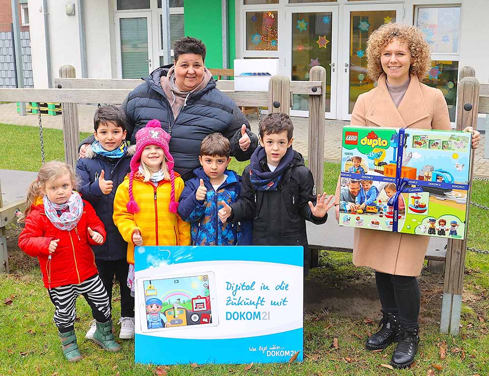 DOKOM21 engagiert sich im Rahmen ihrer sozialen Aktion „Digital in die Zukunft mit DOKOM21“ für Kinder in Dortmund. Der regionale Telekommunikationsdienstleister hat jetzt einen programmierbaren Digi-Zug von Lego und ein iPad als Spende an die Kita des Ev. Familienzentrums Roland in der Dortmunder Nordstadt, Rolandstraße 11, übergeben. Kindern Freude bereiten und vorschulische Bildung fördern „Wir möchten mit unserer sozialen Aktion „Digital in die Zukunft mit DOKOM21“ den Kindern, die zusammen mit ihren Familien von der Coronakrise besonders betroffen sind, eine Freude bereiten und gleichzeitig die vorschulische Bildung fördern. Der programmierbare Digi-Zug von Lego bietet in Verbindung mit der dazugehörigen App tolle Lernmöglichkeiten. Daher spenden wir neben dem Digi-Zug auch gleich noch das passende iPad. So können die Kinder ab sofort alle Möglichkeiten des Digi-Zuges nutzen“, erklärt Helen Waltener, DOKOM21 Marketing. „Wir können den Digi-Zug als kreatives und vielseitiges Lernspielzeug zusammen mit dem iPad in unserer Kita sehr gut einsetzen. Damit können wir unsere Kinder mit und ohne Behinderung auf spielerische Weise an erste Schritte der Programmierung heranführen. Wir möchten die uns anvertrauten Kinder auf ihrem frühen Lebensweg bestmöglich unterstützen und begleiten. Das schließt die digitale Bildung ein“, freut sich Andrea Schaedel, Leiterin des Ev. Familienzentrums Roland in der Dortmunder Nordstadt, über die Spende von DOKOM21. DOKOM21 spendet insgesamt 40 Digi-Züge und 40 iPads an Kinder Im Rahmen der sozialen Aktion „Digital in die Zukunft mit DOKOM21“ für Kinder spendet der regionale Telekommunikationsdienstleister insgesamt 40 Digi-Züge und 40 iPads an Einrichtungen im DOKOM21 Anschlussgebiet, die sich um die Betreuung und Bildung der Kleinsten unserer Gesellschaft kümmern.