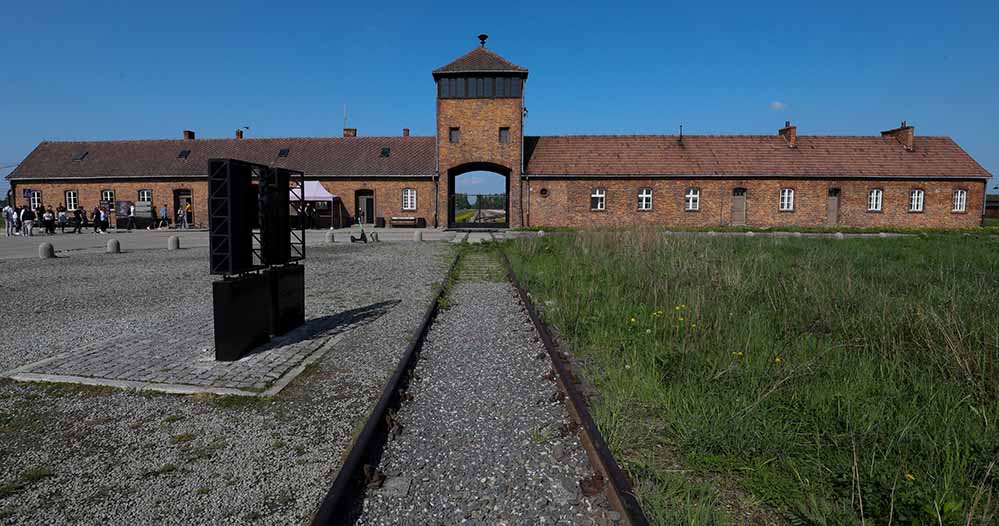Symbol für den Holocaust – das Eingangsgebäude des Vernichtungslagers in Auschwitz-Birkenau mit dem Wachturm und den Gleisen, auf denen die Deportationszüge ankamen.