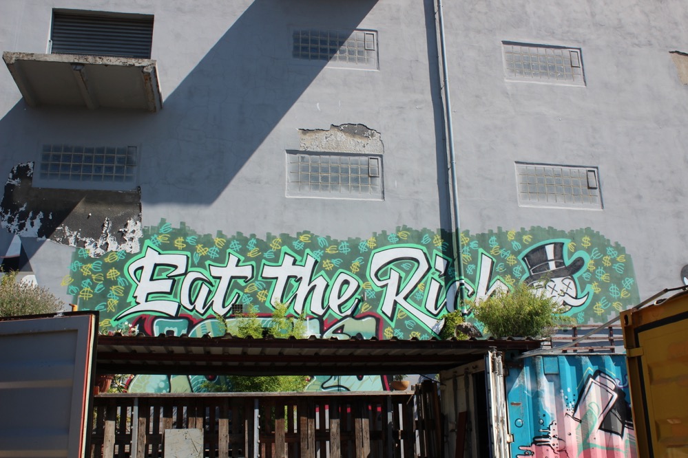 „Eat the rich“ steht es an der Rückwand des Gebäudes in großen Buchstaben.