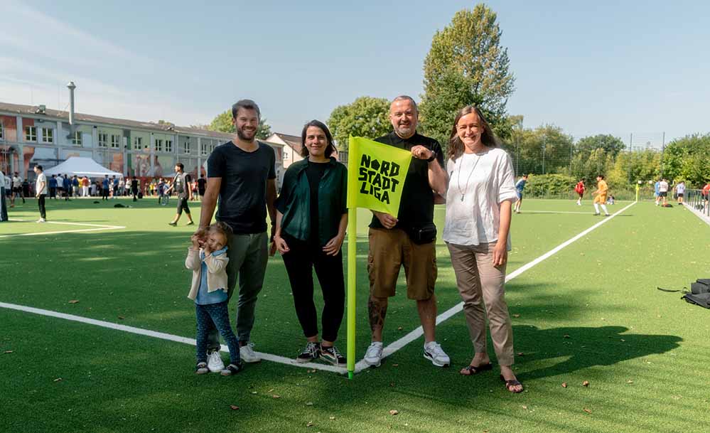 Freuen sich auf das erste Turnier der Nordstadtliga auf dem neu gestalteten Bolzplatz an der Burgholzstraße (von links nach rechts): Martin Eickenscheidt, Projektleiter Grünflächenamt, Hannah Rosenbaum, Bezirksbürgermeisterin Innenstadt-Nord, Mirza Demirović, Beauftragter des Jugendamtes und Heike Junk, Projektleiterin im Amt für Stadterneuerung.