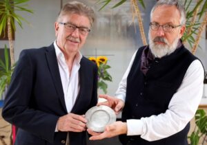 Pfarrer Udo Polenske (li.) aus Hattingen und Kunsthistoriker Ulrich Althöfer freuen sich, dass der Teller wieder in seine Ursprungsgemeinde kommt.