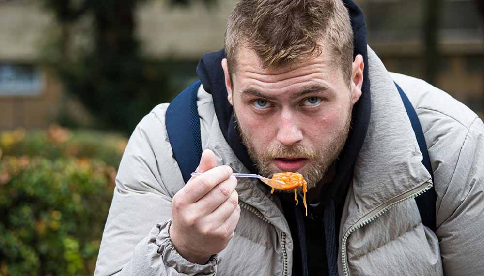 Alexander isst das kostenlose Essen aus der Kana-Suppenküche schnell auf dem Nordmarkt.