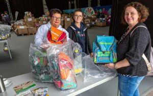 Tanja Henze (re.) von der katholischen Kindertagesstätte Hombruch holte die Tornister ab. Die Ehrenamtlichen Heike Rosenbaum (li.) und Redjije Limani gaben sie aus.