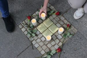 Die Pat:innen der Stolpersteine zünden Kerzen an und legen Rosen nieder.