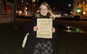 Eine Teilnehmerin mit einem Schild mit der Aufschrift "Menschenrechte statt rechte Menschen"