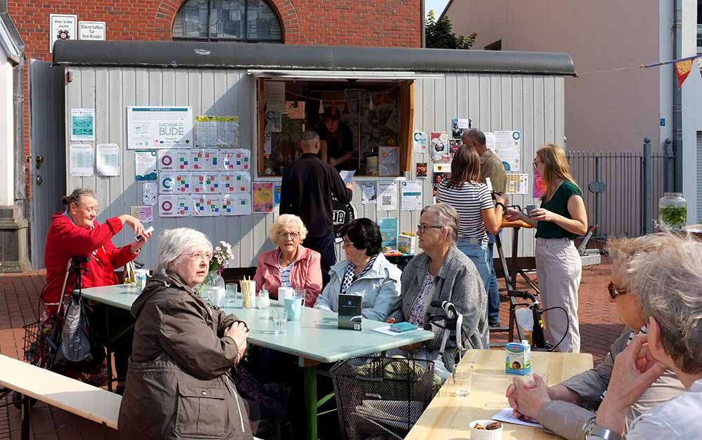 Menschen sitzen in der Sonne auf Bierzeltbänken