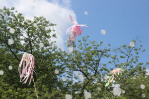 Mit Rauch gefüllte Seifenblasen und Windspiele vor Bäumen und Himmel