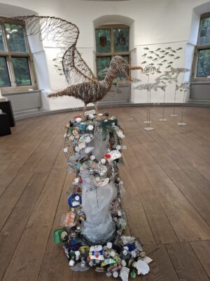 Eine Möwe aus Draht auf einer Säule mit Plastikmüll