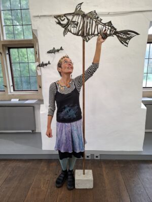 Frau mit einer Skulptur, die einen Fisch darstellt