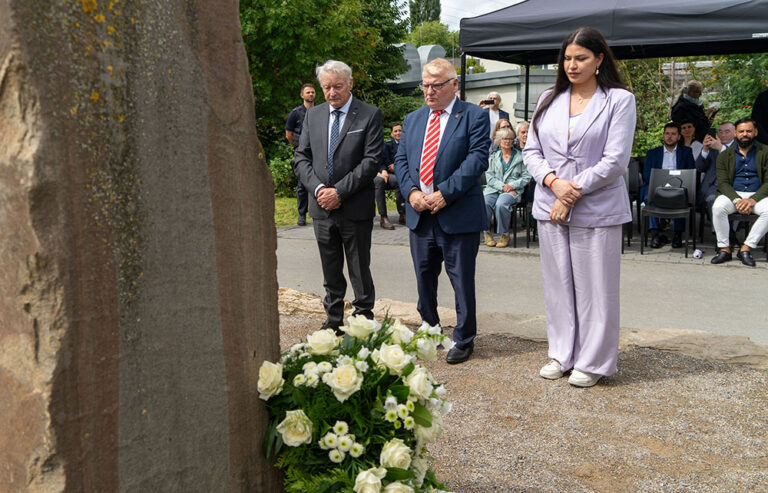 Drei Personen verneigen sich vor dem Gedenkstein.