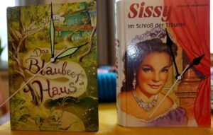 Zwei Bücher mit Zeigern auf dem Titel.