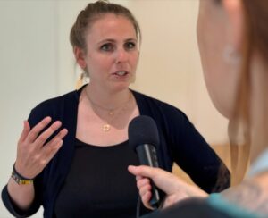 Frau mit schwarzem Oberteil, gestikuliert und spricht