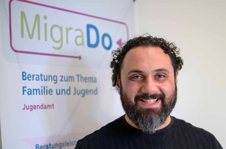 Jamil Alyou lächelnd vor dem MigraDO Aufstellen.