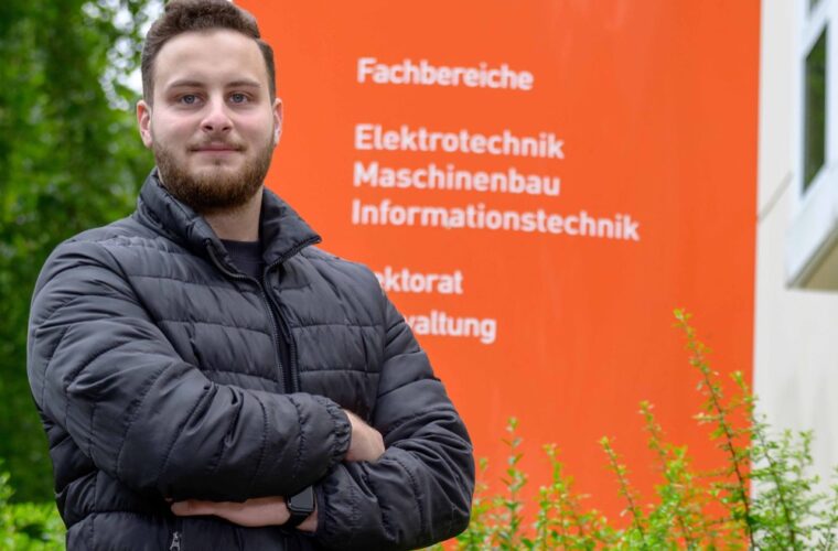 Portrait vor einem Schild der FH