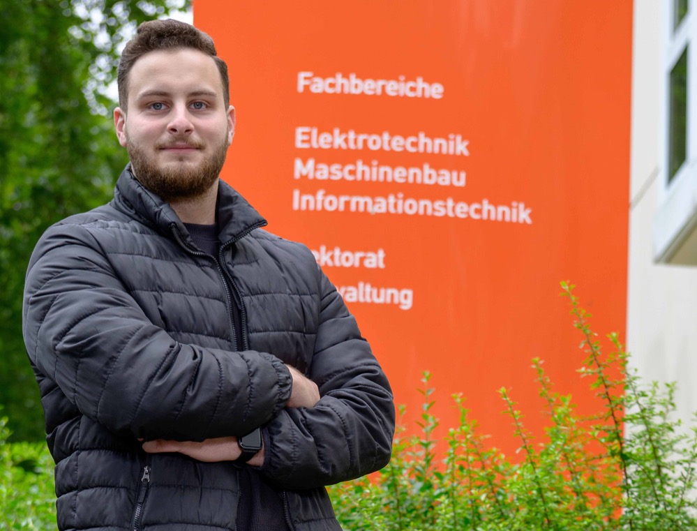 Portrait vor dem Schild an der FH