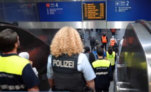 Besuchergruppe mit Polizist:innen und Sicherheitspersonal im Bahnhof