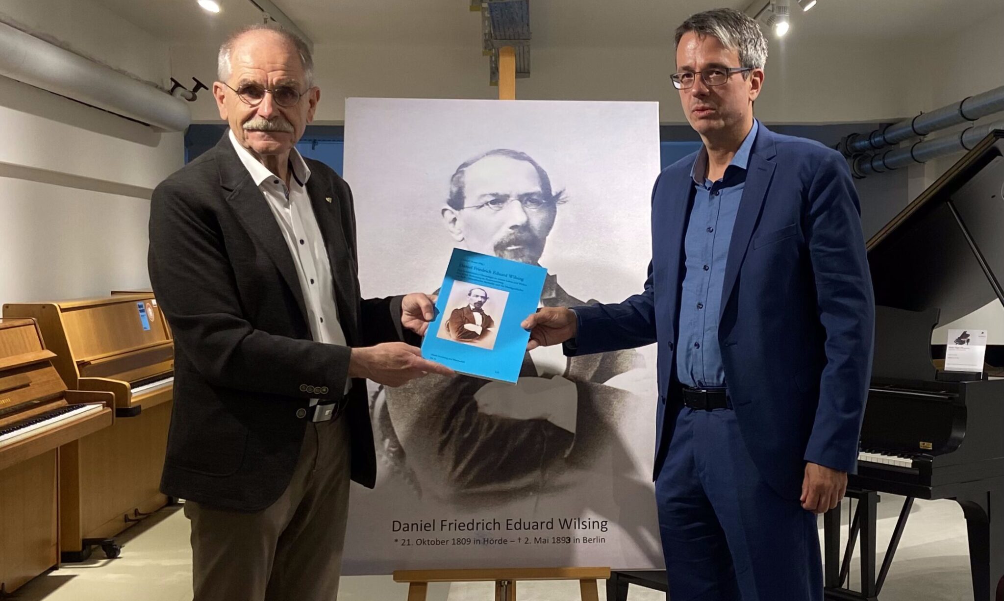 Gerhard Stranz (links) überreicht Dr. Stefan Mühlhofer (rechts) seine Chronologie.