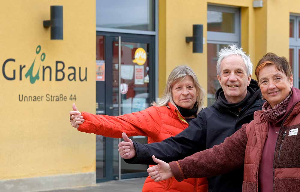 Drei Menschen vor dem Schriftzug