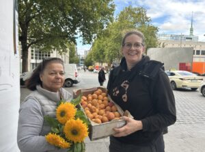 Die zwei Ehrenamtlichen Frauen blicken mit der geretteten Ware in lächelnd in die Kamera.
