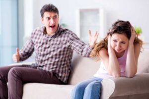 Ein Mann schreit eine junge Frau an, die sich die Ohren zuhält.