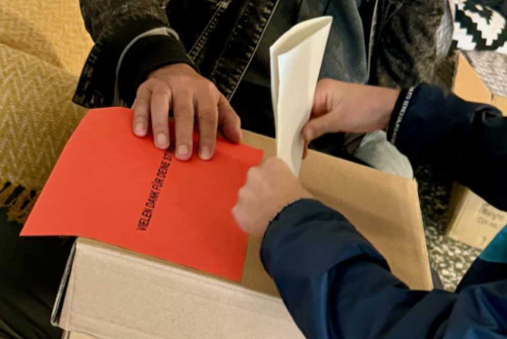 Jugendliche stecken ihren Stimmzettel in die Wahlurne