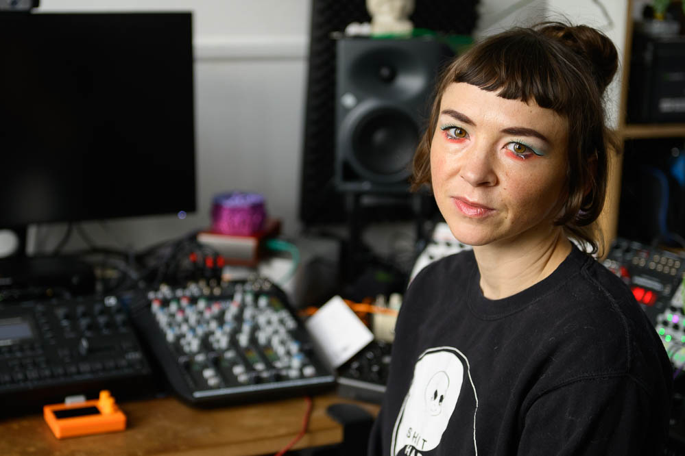 Bild zeigt Jana Kerima Stolzer in ihrem Atelier, im Hintergrund ihr Arbeitsplatz