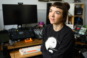 Bild zeigt Jana Kerima Stolzer in ihrem Atelier, im Hintergrund ihr Arbeitsplatz