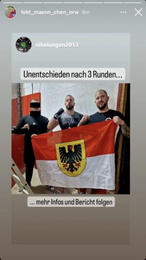 Das Foto zeigt Alexander Deptolla und Steven Feldmann, die eine Dortmund-Flagge halten. Feldmann trägt Bandagen um die Hände, er kommt gerade aus einem Boxkampf, den er für den KdN angetreten hat.