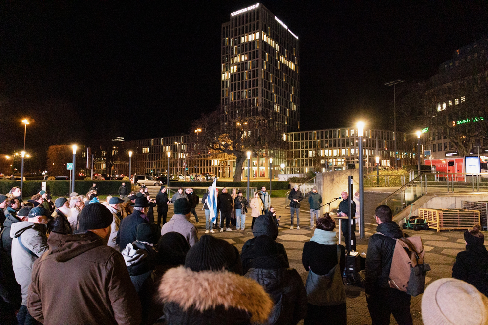 Das Foto zeigt Menschen, die in einem Halbkreis auf dem Platz der AltenSynagoge stehen.